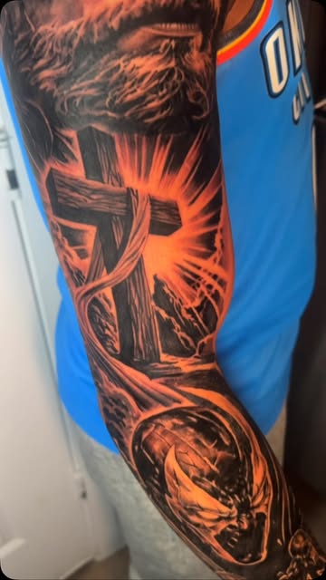 Dark realism tattoo with a cross and dramatic orange-lit sky