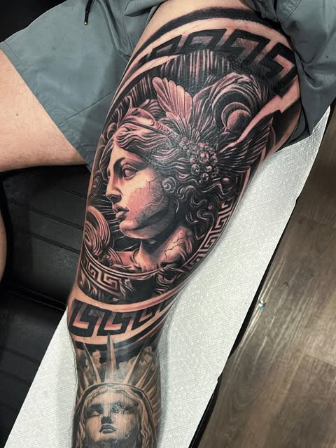 Black and grey mythological portrait and Statue of Liberty leg tattoo
